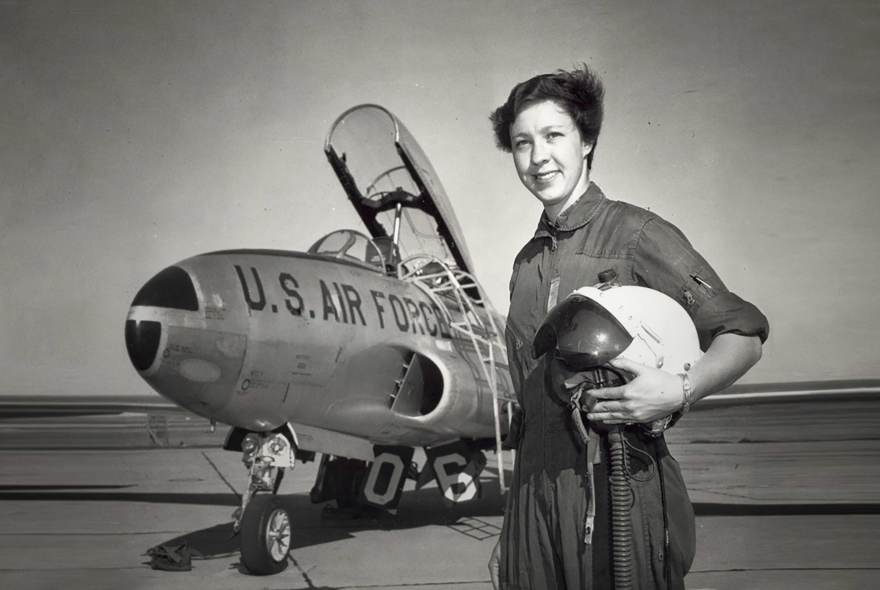 A black and white image of Wally Funk standing beside a US Air Force aircraft.